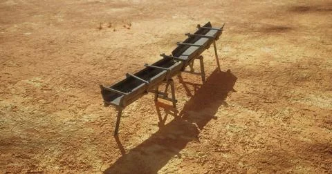 Metal frame structure placed on dry, barren ground in a sunny outdoor setting Ilustración de archivo