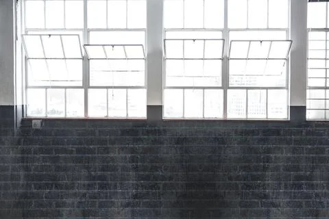 Metal-framed windows flooding with daylight, dark-gray-brick wall with outlet, Stock Illustration