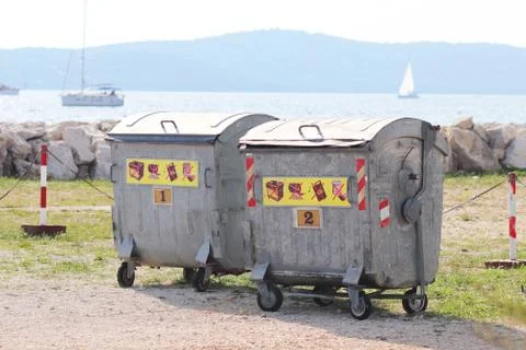 Metal garbage cans for waste sorting stand on the pier in the marina against  Stock Photos