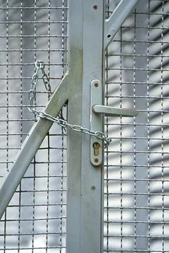 The metal gate made of chain-link fencing is equipped with a handle and a l.. Photos