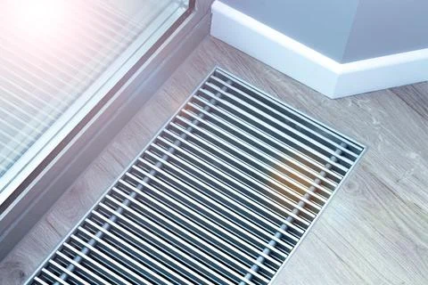 Metal grate for convector heating in the floor next to the window. Stock Photos