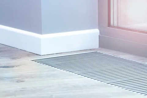 Metal grate for convector heating in the floor next to the window. Stock Photos