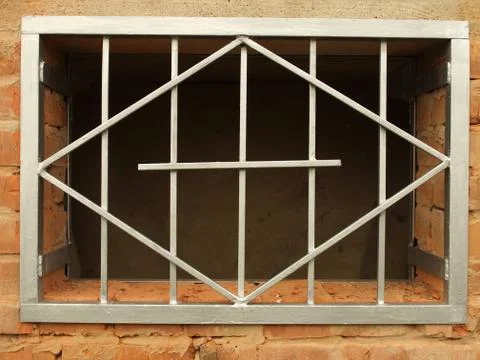 Metal grid in the window a brick wall Stock-Fotos