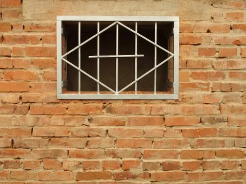 Metal grid in the window a brick wall Stock Photos
