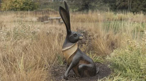 Metal hare in a garden of dry grass Stock Photos