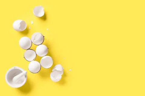 Metal holder with egg shells and mortar on yellow background Foto stock
