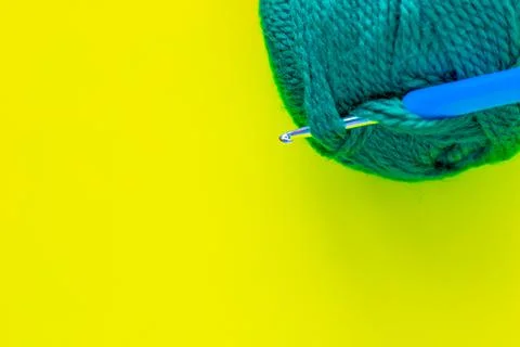 A metal hook with a blue handle is inserted into a skein of green yarn 写真素材