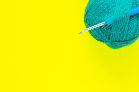 A metal hook with a blue handle is inserted into a skein of green yarn Stock Photos