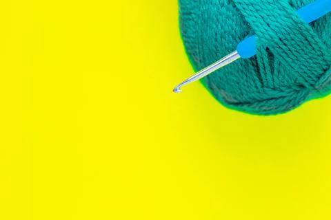 A metal hook with a blue handle is inserted into a skein of green yarn in the 写真素材