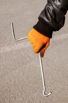 Metal jack handle in the hands of a man wearing orange gloves and a black twi Stock Photos