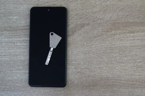 Metal key on a smartphone screen, security concept Stock Photos