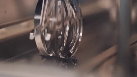 Metal machine hook slowly pulling lenses on rode out liquid at manufactory Stock Footage 76570757