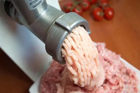 Metal meat grinder scrolls meat close-up. Homemade mincemeat. Stock Photos