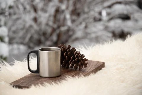 Metal mug and pine cone on wooden board outdoors Stock Photos