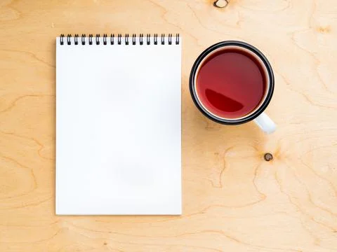 Metal mug with tea, empty a blank sheet of notepad on the spiral on a beige Stock Photos