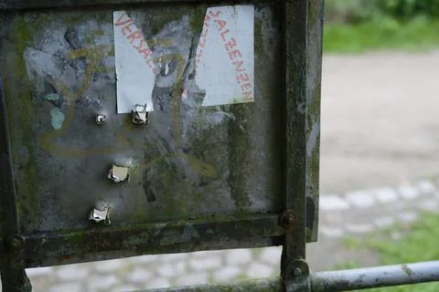 Metal notice board with four ragged bullet holes and torn flyer Stock Photos