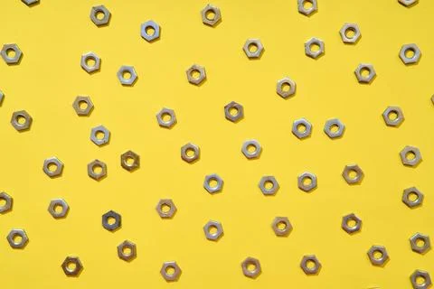Metal nuts pattern on yellow background 写真素材