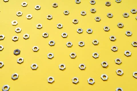 Metal nuts pattern on yellow background 写真素材