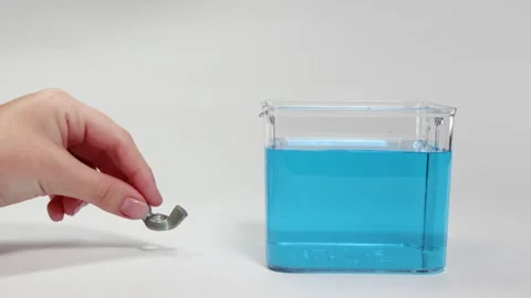 Metal Object Sinking in Blue Liquid Experiment Video stock 308446249