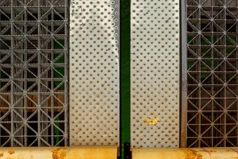 Metal panels with patterns standing in front of a wall with rust and green .. Photos