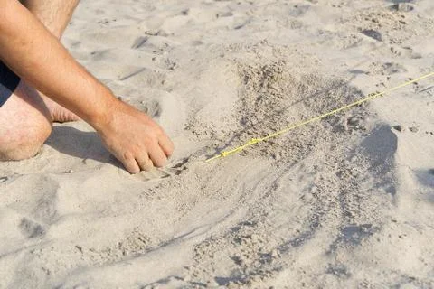 A metal peg driven into the sand to pull the rope out of the tent. Camping on a Stock Photos
