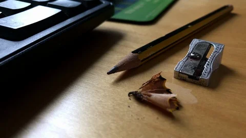 Metal pencil sharpener lying next to pencil and pencil sharpening on a table Stock Footage 107599493