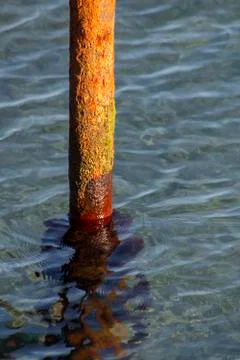 Metal pipe covered with rust in the sea. Stock Photos