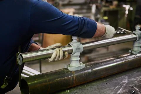 Metal pipe in the hands of a worker in the workshop for the manufacture of lamp Stock Photos