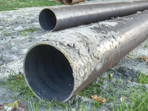 Metal pipe stack on soil. Rounded iron pipe shape ready for use. Stock Photos