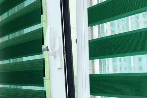 Metal plastic windows with blinds, close up view on handle with a lock. The Stock Photos