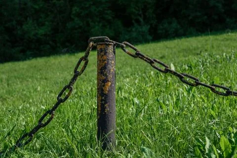 A metal pole with two chains among the grass. Stock Photos