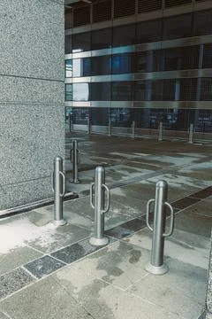 Metal posts stand in front of a modern building with glass walls in a city .. Stock Photos