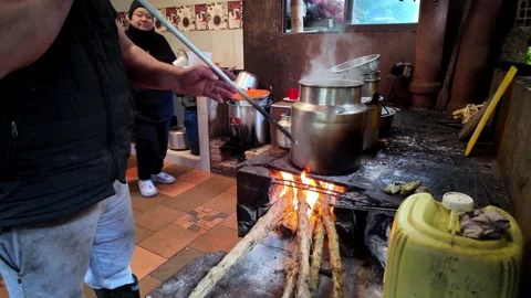 Metal pot boiling over an active wood fired stove in a rustic roadside kitchen Stock Footage 335920454