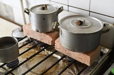 Metal pot elevated with bricks on stove, Stock Photos