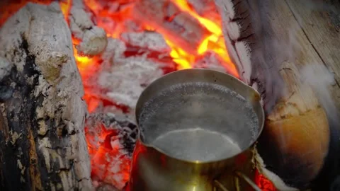 Metal pot heating over hot burning campfire embers in the forest. Stock Footage 341977855
