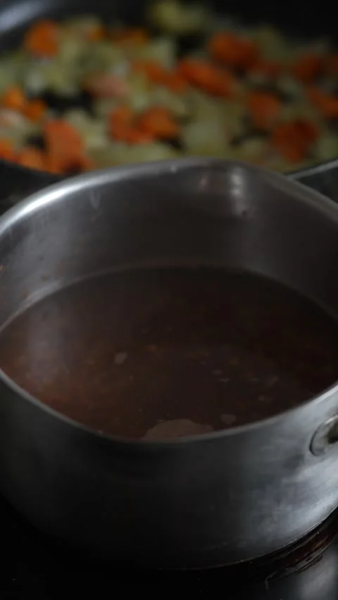 A metal pot stands in focus with fried vegetables behind. Stock Footage 344134903