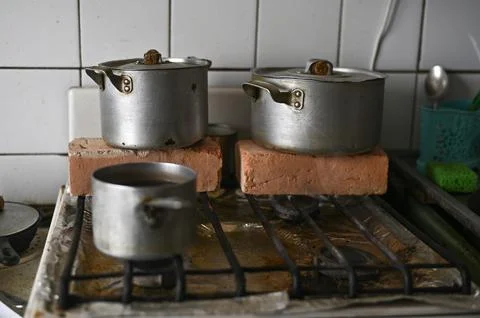 Metal pots on stove, elevated with bricks for makeshift heating, Stock Photos