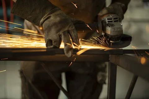 Metal processing with a grinder. Sparks from the tool. A man in the workshop  Stock Photos