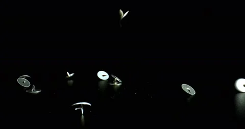 Metal Push Pins falling in slow motion on black reflective surface Stock Footage 142771269