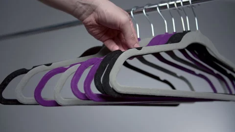From a metal rack with empty clothes hangers, a man takes one of them Stock Footage 157280330