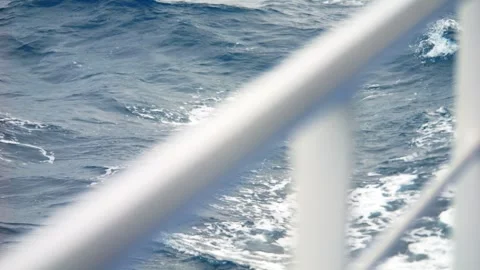A metal railing frames the waves below, adding depth to the dynamic seascap.. Stock Footage 291589285