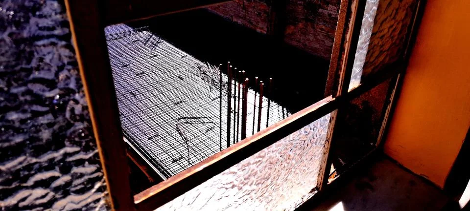 Metal rebar grid framework viewed through an old textured window frame Foto stock