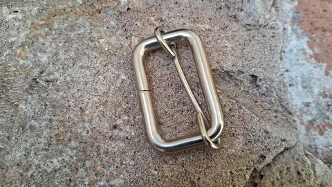 Metal rectangular buckle on stone surface. Industrial hardware fastener for bags Stock Photos