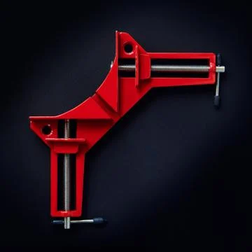 Metal red corner clamp on dark background, top view, tool Stock Photos