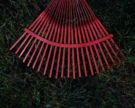 Metal red rake on a  grass, close-up Stock Photos