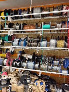 Metal ropes cables and chains coiled and stored in bobbins inside a buildin.. Photos