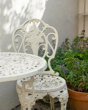 Metal rustic white table and chairs with plant in background, exterior patio Stock Photos