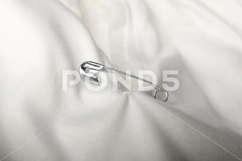 Metal safety pin on white fabric, closeup Stock Photo #200869380