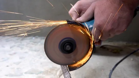 A metal saw with a disc grinder in a workshop. Sparks fly out of the circle Stock Footage 115438517