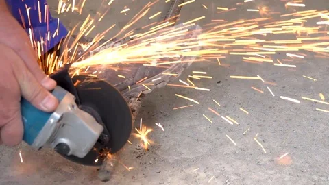 A metal saw with a disc grinder in a workshop. Sparks fly out of the circle Stock Footage 115439470